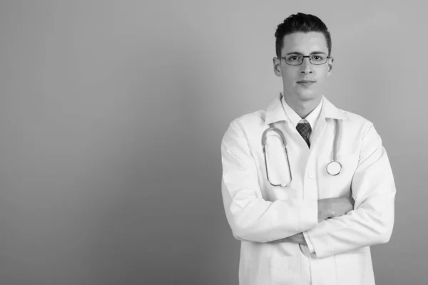 Fiatal jóképű férfi orvos ellen szürke háttér — Stock Fotó