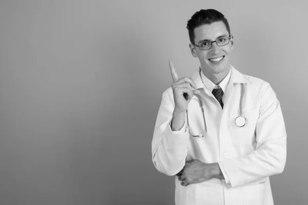 Joven hombre guapo médico contra fondo gris — Foto de Stock