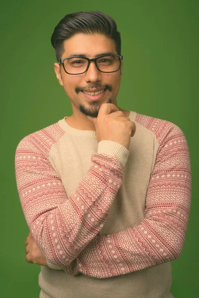 Young bearded Iranian man against green background