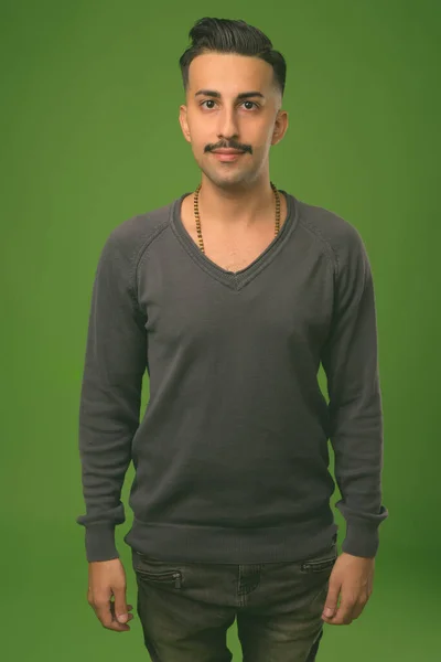 Jovem iraniano bonito com bigode contra fundo verde — Fotografia de Stock