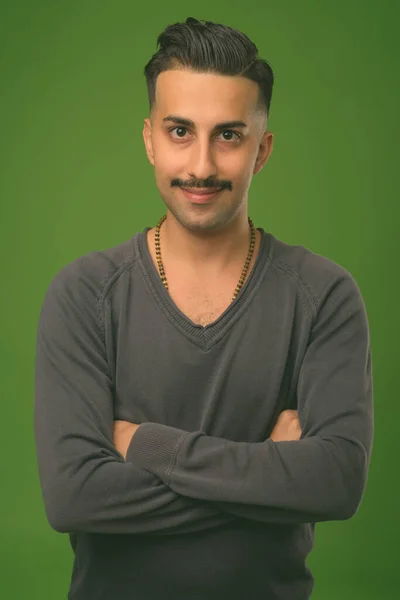 Jonge knappe Iraanse man met snor tegen groene achtergrond — Stockfoto