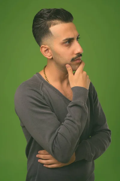 Молодой красивый иранский мужчина с усами на зеленом фоне — стоковое фото