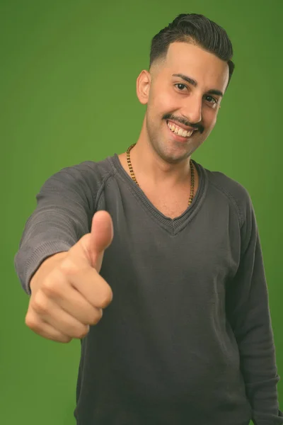 Jovem iraniano bonito com bigode contra fundo verde — Fotografia de Stock