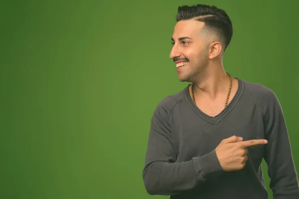 Junger schöner iranischer Mann mit Schnurrbart vor grünem Hintergrund — Stockfoto