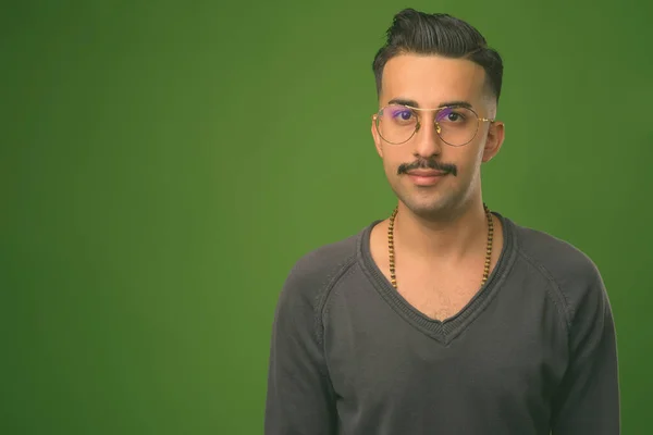 Jovem iraniano bonito com bigode contra fundo verde — Fotografia de Stock