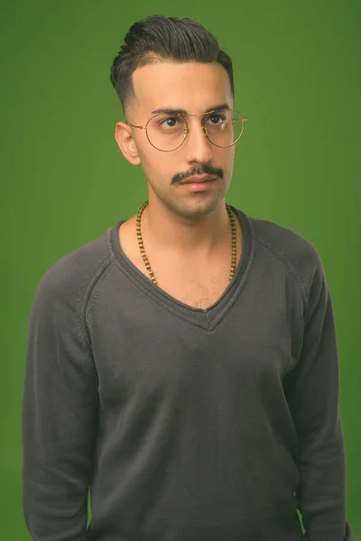 Młody przystojny Irańczyk z wąsami na zielonym tle — Zdjęcie stockowe