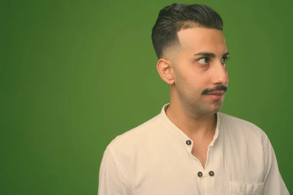 Молодий гарний іранський чоловік з вусами на зеленому фоні. — стокове фото