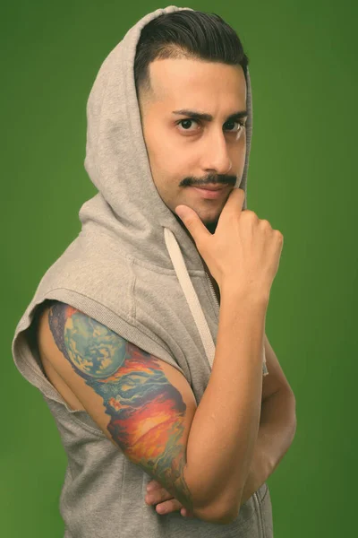Young handsome Iranian man with mustache against green background — Stock Photo, Image
