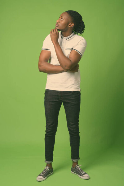 Studio shot of young handsome African man from Kenya against green background