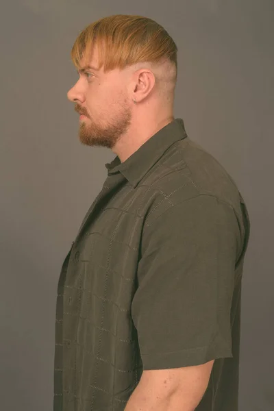 Vousatý muž s blond vlasy proti šedému pozadí — Stock fotografie