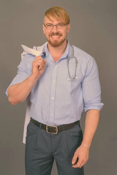 Бородатий чоловік лікар з світлим волоссям на сірому фоні — стокове фото