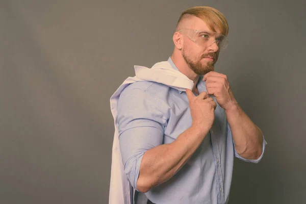 Hombre barbudo doctor con cabello rubio usando gafas protectoras contra fondo gris —  Fotos de Stock