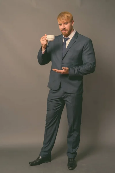 Бородатый бизнесмен с светлыми волосами на сером фоне — стоковое фото