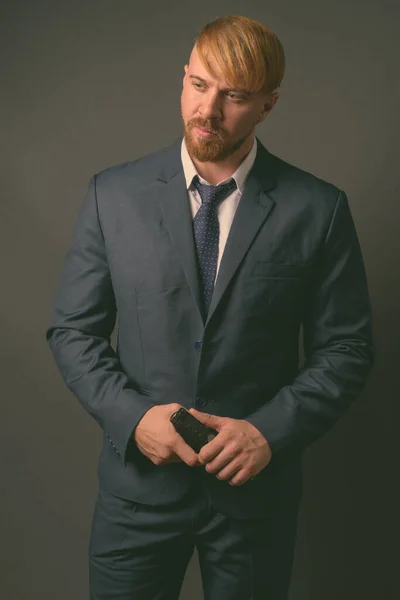 Bearded businessman with handgun against gray background — Stock Photo, Image