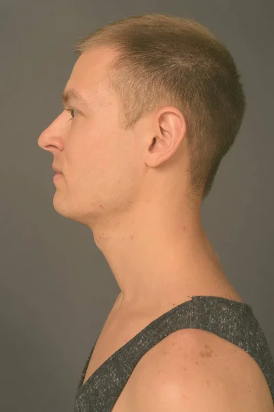 Portrét mladého pohledného muže na šedém pozadí — Stock fotografie