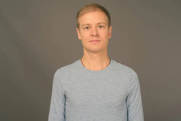 Retrato de homem bonito jovem contra fundo cinza — Fotografia de Stock