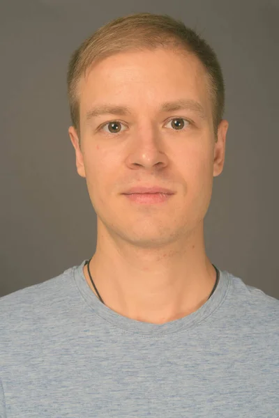 Retrato de homem bonito jovem contra fundo cinza — Fotografia de Stock