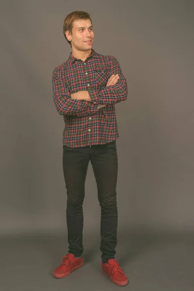 Portrait of young handsome man against gray background — Stock Photo, Image