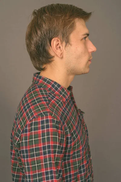 Portrét mladého pohledného muže na šedém pozadí — Stock fotografie