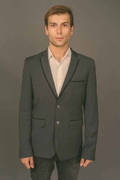 Portrait of young handsome businessman against gray background — Stock Photo, Image