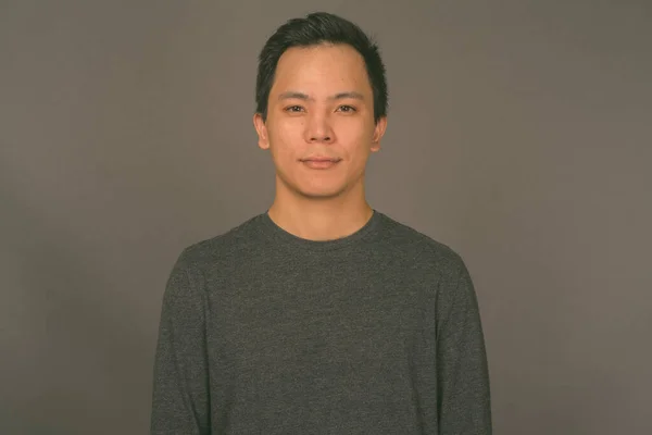 Portrait of young handsome man against gray background — Stock Photo, Image