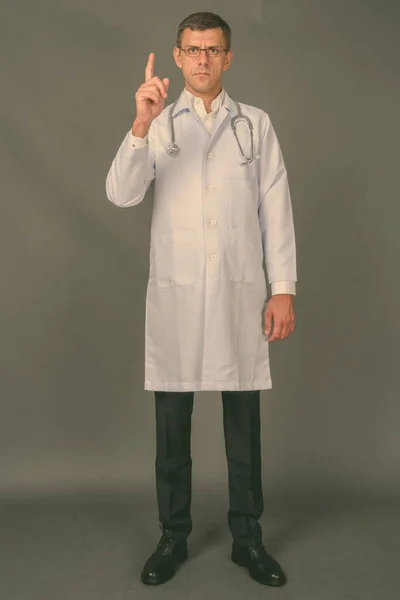 회색 배경에 대해 짧은 머리를 하고 있는 다루기 쉬운 남자 의사 — 스톡 사진