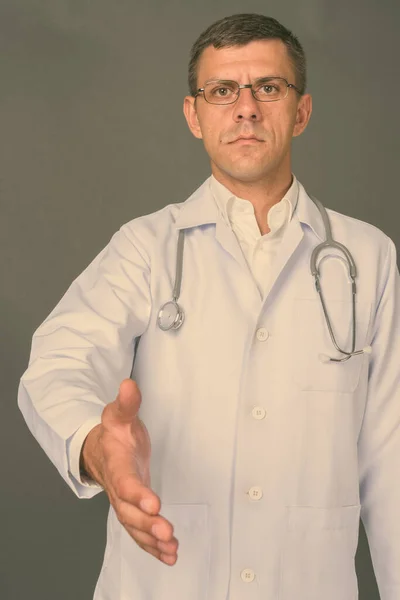 Pohledný muž lékař s krátkými vlasy proti šedému pozadí — Stock fotografie