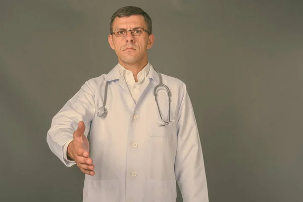 Красивий чоловік лікар з коротким волоссям на сірому фоні — стокове фото