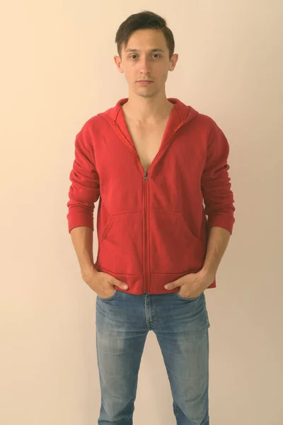 Studioaufnahme eines jungen, gut aussehenden Mannes, der roten Kapuzenpulli vor weißem Hintergrund trägt — Stockfoto