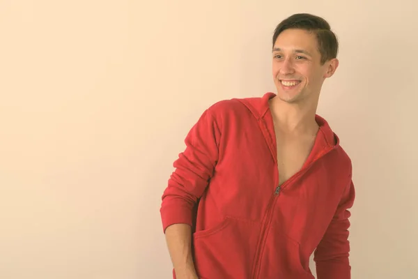 Studio shot of happy young handsome man smiling while looking to the side against white background — Stock Photo, Image
