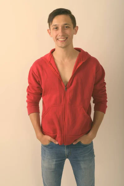 Estudio disparo de joven hombre guapo feliz sonriendo, mientras que de pie sobre fondo blanco —  Fotos de Stock