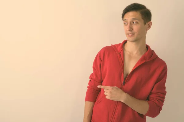 Studio shot of young handsome man looking and pointing to the side against white background — Stock Photo, Image