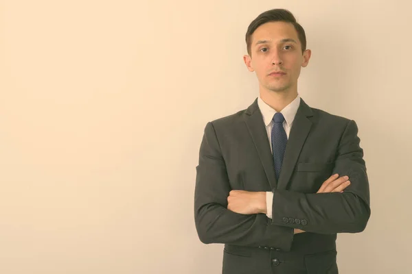 Studio shot of young handsome businessman with arms crossed against white background — Stock Photo, Image