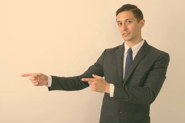 Studio shot van jonge knappe zakenman tonen iets terwijl wijzend vingers tegen witte achtergrond — Stockfoto