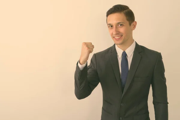 Studio shot van jonge gelukkige zakenman glimlachen terwijl op zoek gemotiveerd tegen witte achtergrond — Stockfoto