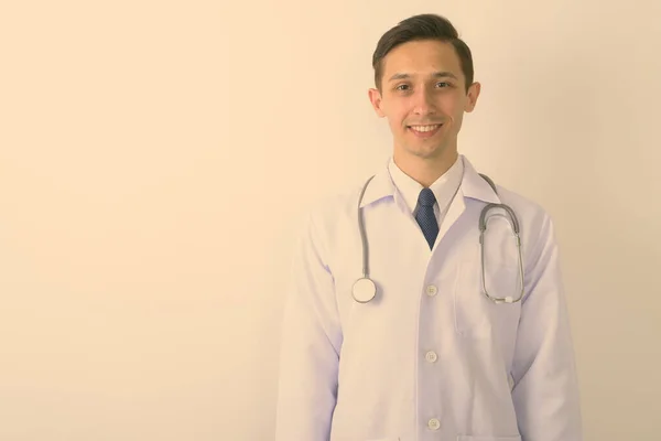 Estúdio tiro de jovem médico homem feliz sorrindo contra fundo branco — Fotografia de Stock