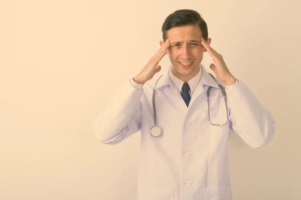 스트레스를 받은 젊은 의사가 하얀 배경에 두 통을 겪고 있는 스튜디오 촬영 — 스톡 사진