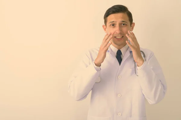 Studio záběr mladý pohledný muž lékař vypadá šokován proti bílému pozadí — Stock fotografie