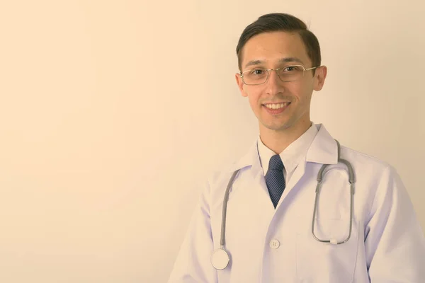 Gros plan du jeune homme heureux médecin souriant tout en portant des lunettes sur fond blanc — Photo