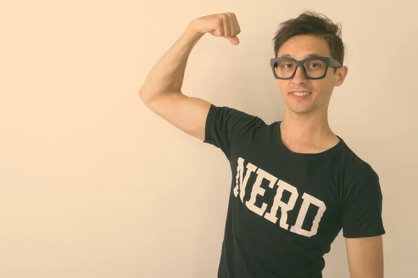 Studioaufnahme eines jungen glücklichen Nerd-Mannes, der lächelnd den Arm beugt und eine Brille vor weißem Hintergrund trägt — Stockfoto