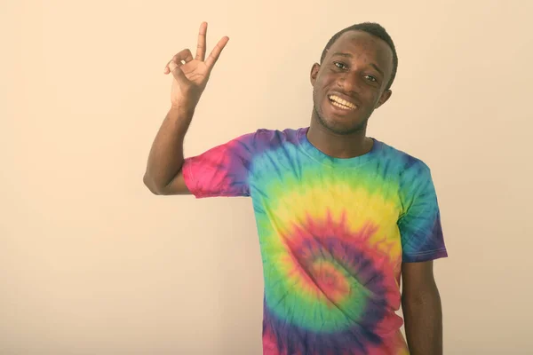 Estudio disparo de joven feliz negro africano sonriendo y haciendo señal de paz sobre fondo blanco — Foto de Stock