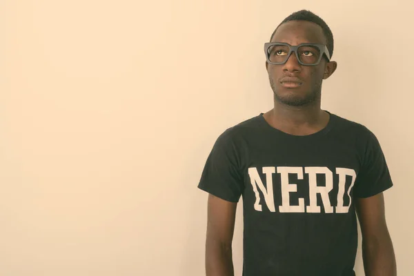 Studio shot of young black African geek man wearing Nerd shirt while thinking and looking up against white background — Stock Photo, Image