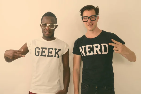 Estúdio tiro de jovem negro feliz Africano Geek homem com europeu Nerd homem contra sorrir e fazer sinal de paz — Fotografia de Stock