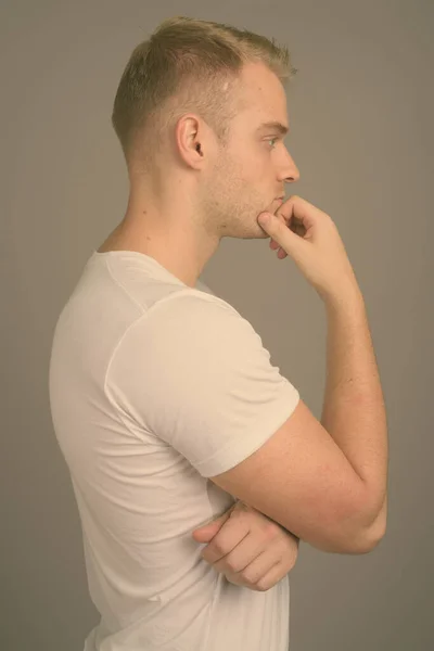Sarı saçlı, gri arka planda genç yakışıklı bir adam. — Stok fotoğraf