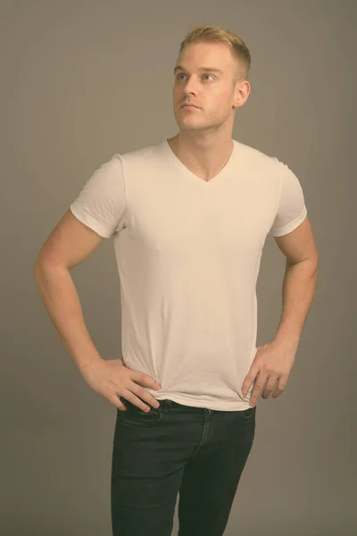 Jovem homem bonito com cabelo loiro contra fundo cinza — Fotografia de Stock