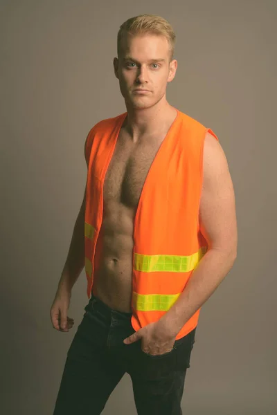Joven hombre guapo trabajador de la construcción sin camisa sobre fondo gris —  Fotos de Stock