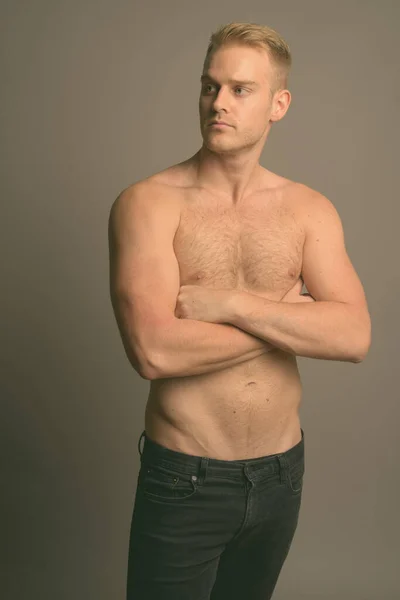 Joven hombre guapo con el pelo rubio sin camisa sobre fondo gris — Foto de Stock