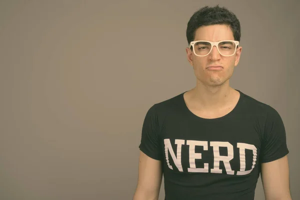 Joven hombre nerd guapo con anteojos sobre fondo gris — Foto de Stock