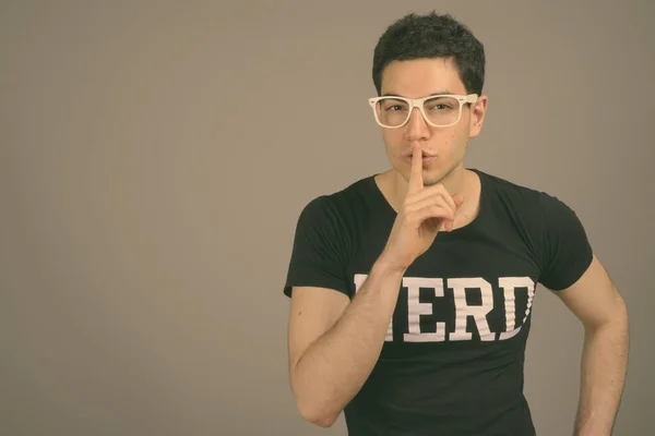 Young handsome nerd man with eyeglasses against gray background — Stock Photo, Image