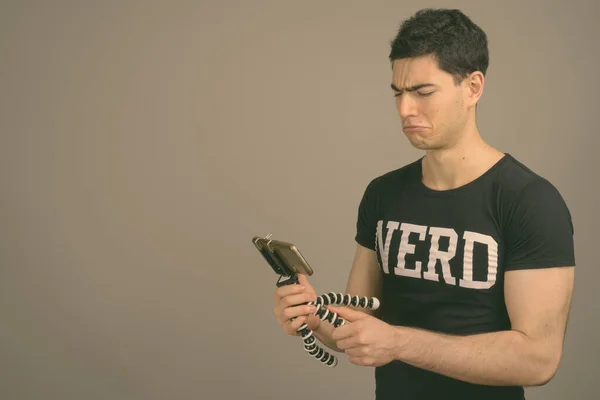 Young handsome nerd man against gray background